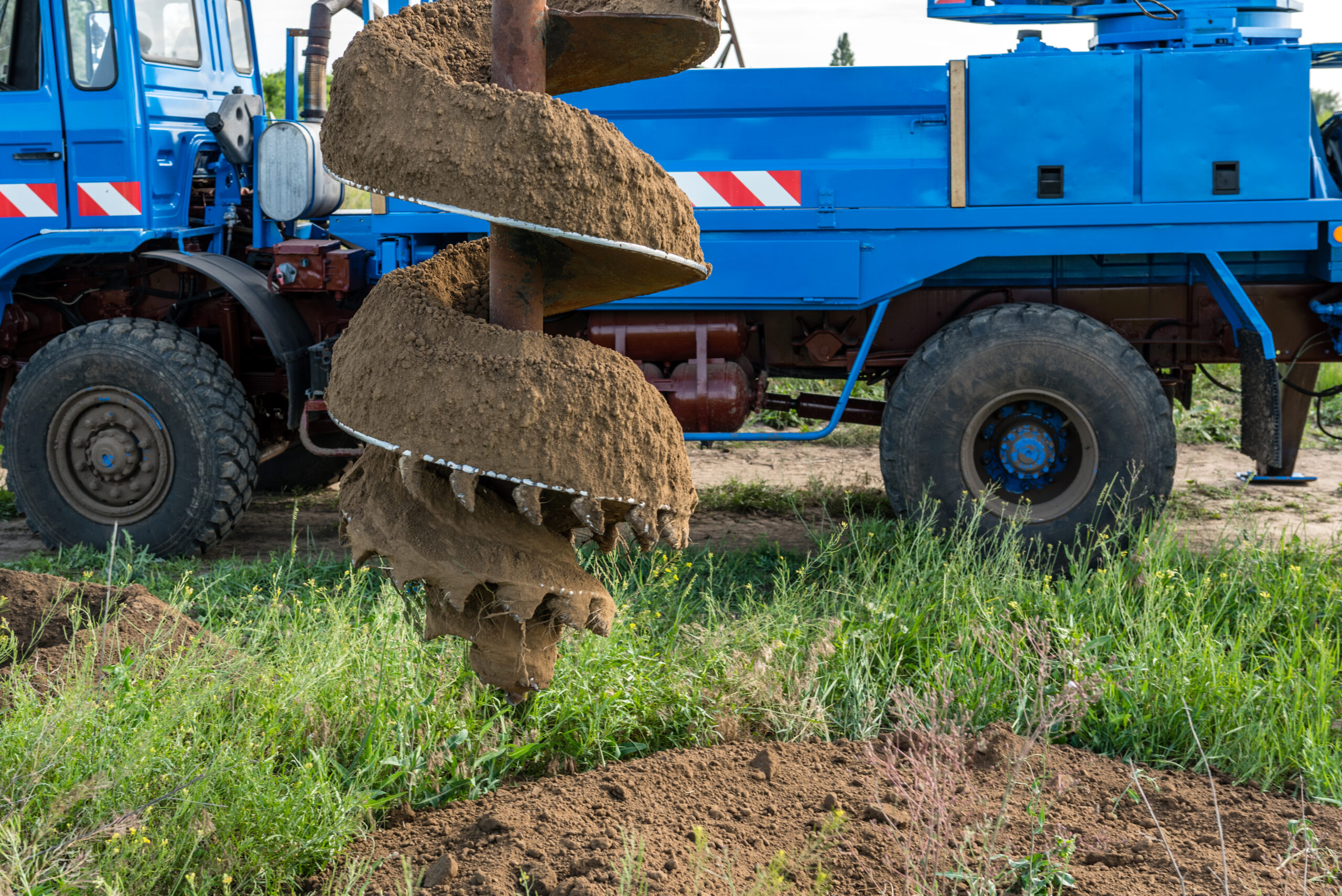 Tracer tractor with auger for soil drilling for piles installation during construction of buildings and structures